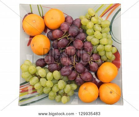 tangerines and grapes in a bowl on a white background