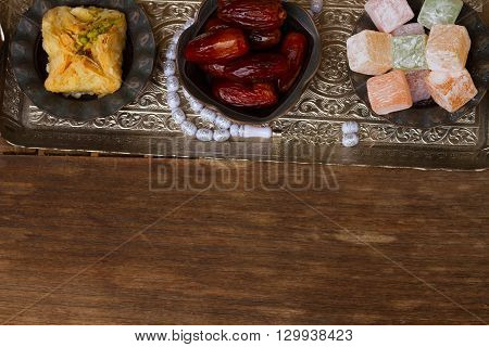 Turkish delights with tasbih on silver oriental tray border with copy space on wooden background