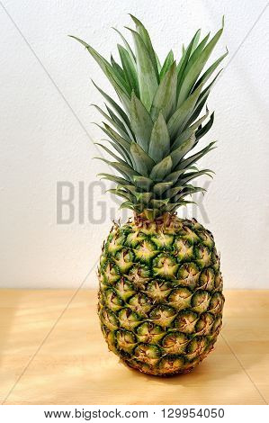 Pineapple on wooden table with white wall background