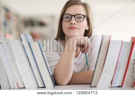 portrait of smart looking famale student girl  in collage school library,  selecting book to read from bookshelf