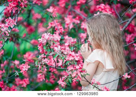 Adorable little girl in blooming apple garden on beautiful spring day