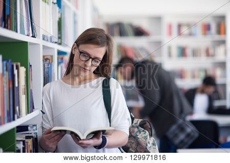 portrait of smart looking famale student girl  in collage school library reading book