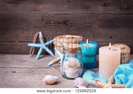 Сandle and marine decorations on aged wooden background. Sea objects on wooden planks. Selective focus.Toned image.