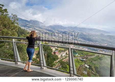 Woman looking at Madeira landscape from Cabo Girao famous viewpoint. Cabo Girao is the highest cliff in Europe. Madeira island, Portugal.