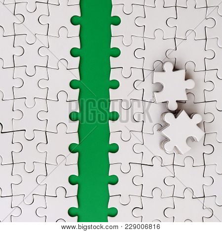 The Green Path Is Laid On The Platform Of A White Folded Jigsaw Puzzle. The Missing Elements Of The 