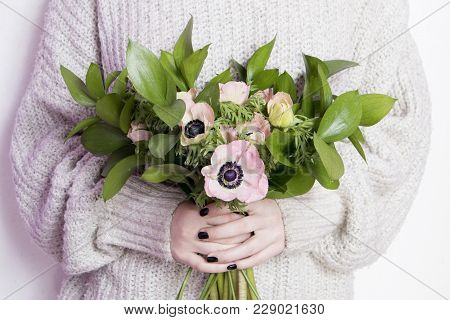 The Girl In White Wool Sweater Holds A Wedding Bouquet Of Anemones And Ruscus On The White Backgroun