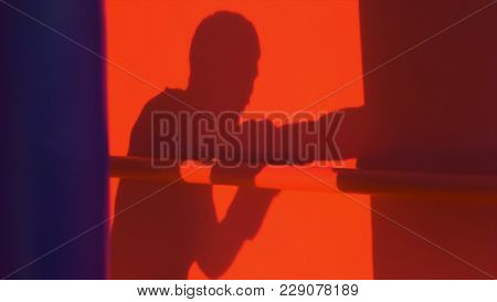 Silhouette Or Shadow Of A Boxer Punching A Punching Bag Close Up, Red Light Background. Silhouette O