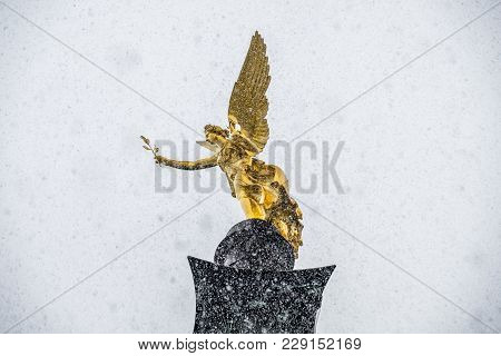 The Angel Of Peace On The Top Of Friedensengel Monument In Munich, Germany During The Snow Srorm.