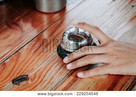 Hand Of A Woman Using A Restaurant Bell.selective Focus.