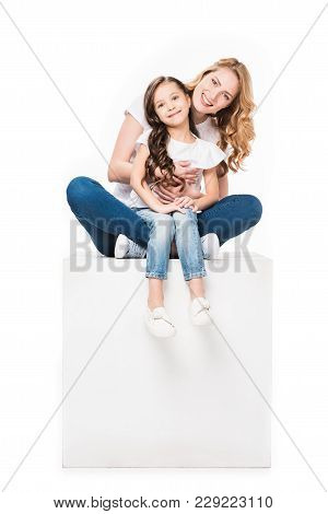 Mother And Daughter Sitting On Empty White Cube Isolated On White