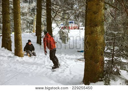 Mummelsee, Germany - Feb 18, 2018: Winter Scene With Young Adult On The Snowboard And Young Boy Admi