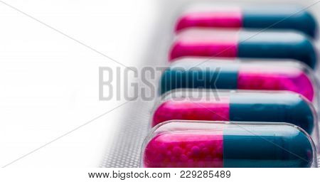 Selective Focus Of Blue, Pink Capsule With Granule In Side Pills. Pills In Blister Pack On White Bac