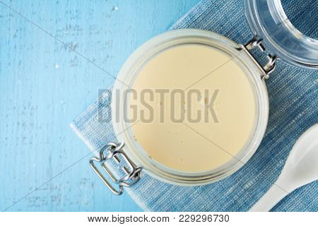Jar With Condensed Milk Or Evaporated Milk On Blue Table Top View.