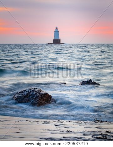 Sakonnet Point Lighthouse Golden Hour Sunset Seascape With Smooth Silky Water And Rocky Foreground.