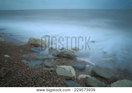 Stones On The Pebble Beach With Blurred Sea Waves Near Town Of Seaton In East Devon On The Jurassic 