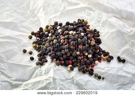 Black Pepper Peas On A Wooden Spoon Against Crumpled Paper Background