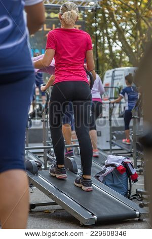 Woman In Sportswear Exercising Outdoor On Treadmill.