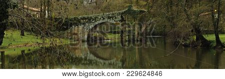 Roman Bridge Reflected On The River Arnoia, Allariz, Galicia. Spain