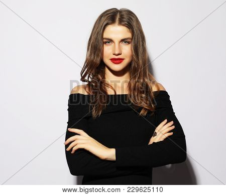 Blond woman in black dress posing with crossed arms and looking 