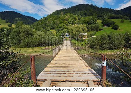 Suspension Bridge Over River. Long Rope Bridge Cross The Stream In The Village