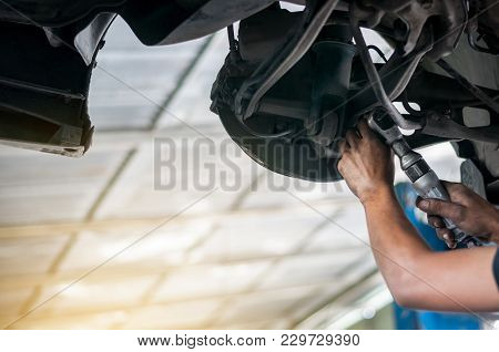 Auto Mechanic Asian Checking Bush-bolt Under Double Wishbone Suspension By Hand With Tools Car Lift