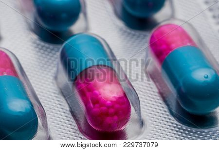 Selective Focus Of Blue, Pink Capsule With Granule In Side Pills. Pills In Blister Pack On White Bac