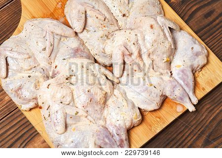 Raw Quails In Spices On A Wooden Background.