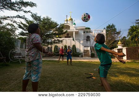 KOH CHANG, THAILAND - FEB 25, 2018: Thai children play in ball near the Russian Orthodox Church. There are currently 10 Orthodox parishes in Thailand, Orthodoxy is practiced by 0.002% of population.