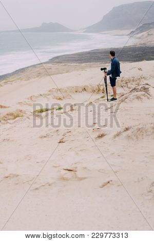 Photographer With Camera In Desert Admitting Unique Landscape Of Sand Dunes Volcanic Cliffs On The A