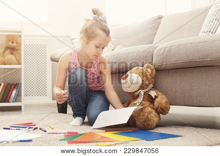 Happy Little Girl Drawing. Cute Kid Sitting At Home On The Floor Among Cologed Paper And Pencils. Di