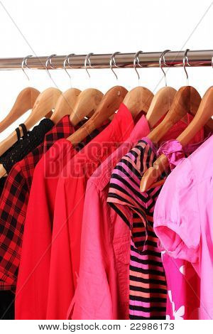 เสื้อผ้าที่แตกต่างกันบน hangers แยกต่างหากบนพื้นสีขาว