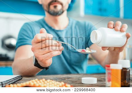 Correct Dose. Expensive Colorful Pills Being In The Spoon Which Man Holding In His Hand.