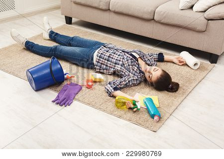 Tired Woman Lying On Carpet After Cleaning Home In The Living-room, Copy Space. Housekeeping And Hom