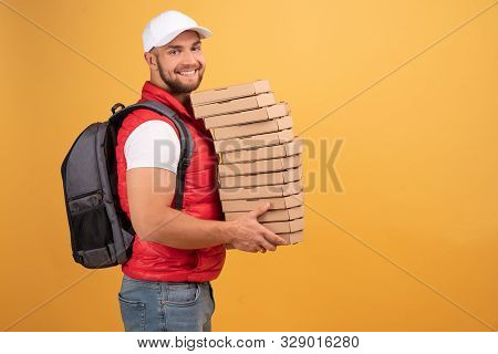 Cheerful Pizza Delivery Man Stands In Profile With Carton Boxes, Waits For Client, Wears White Cap A