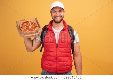 Cheerful Pizza Delivery Man Stands With Carton Box With Pizza, Waits For Client, Wears White Cap And