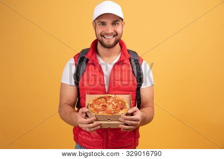 Cheerful Pizza Delivery Man Stands With Carton Box With Pizza, Waits For Client, Wears White Cap And