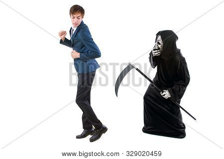 Man In A Halloween Grim Reaper Ghost Costume Chasing, Mocking And Making Fun Of Scared Businessman R