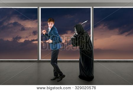 Man In A Halloween Grim Reaper Ghost Costume Chasing, Mocking And Making Fun Of Scared Businessman R