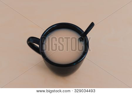 Chai Tea With Milk In Black Mug On Wooden Table Of The Same Color