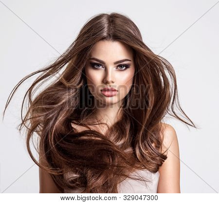 Portrait of a beautiful woman with a long hair. Young  brunette model with  beautiful hair - isolated on white background. Young girl with hair flying in the wind.