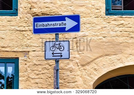 One Way Street Sign In Germany Against Urban Background.
