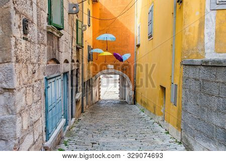 Croatia, Istria, Beautiful Old Cobbled Street, Traditional Houses And Umbrellas Decorations In The O