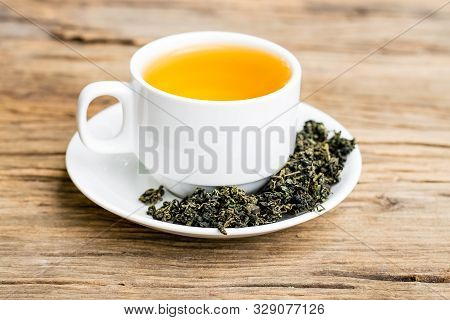 Dry Gynostemma Pentaphyllum Leaf With Brewed Tea In A White Cup On The Wood Floor