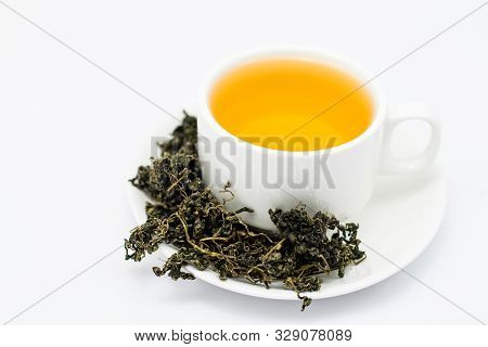 Dry Gynostemma Pentaphyllum Leaf With Tea Brewed In A White Cup On White Blackground