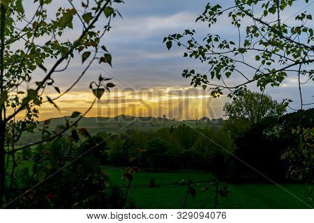 Rising Sun Lights Up Landscape Through Gap In Clouds