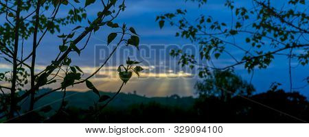 Rising Sun Lights Up Landscape Through Gap In Clouds