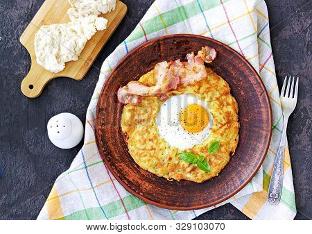 Potato Hash Brown With Egg And Bacon On A Brown Clay Plate On A Dark Concrete Background. American C
