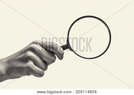 Female Hand Holding The Magnifying Glass On Isolated Background. Black And White Image.
