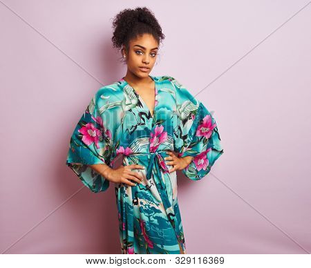 Young beautiful african american woman standing wearing elegant colorful caftan