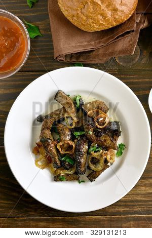 Close Up Of Fried Beef Liver With Onion On Plate Over Wooden Background. Pieces Cooked Liver (offal)
